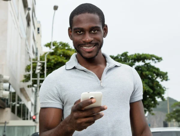 Afrikanischer Mann mit Bart sendet Nachricht mit Telefon — Stockfoto