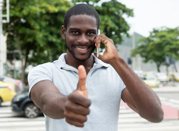 Skrattande afrikanska man med skägg på telefonen visar tummen — Stockfoto