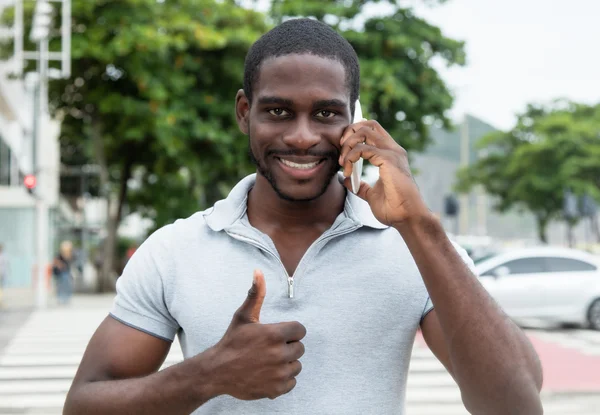 Hombre africano con barba en el teléfono mostrando el pulgar hacia arriba — Foto de Stock