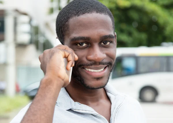 Hombre africano con barba riendo por teléfono —  Fotos de Stock