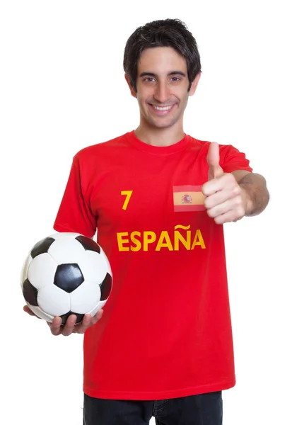 Испанский футбольный фанат с черными волосами и шаром, показывающий большой палец вверх — стоковое фото