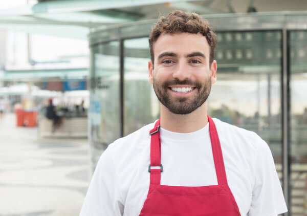 Laughing waiter with beard in front of a restaurant