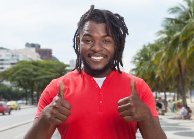 Her iki başparmak gösterilen City dreadlocks ile Afrika kökenli Amerikalı adam