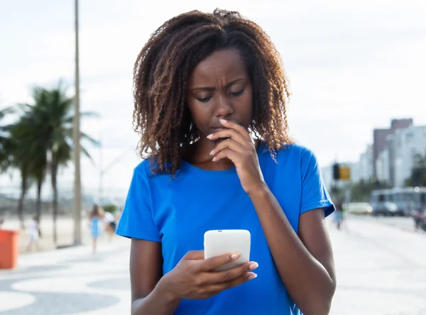 Pensando mujer africana en una camisa azul con teléfono —  Fotos de Stock