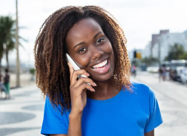 Mulher africana feliz em uma camisa azul ao ar livre no telefone — Fotografia de Stock