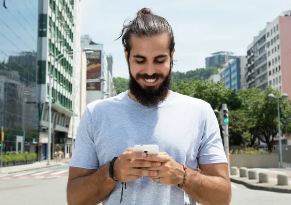 Arap adam sakallı ve kırmızı gömlek şehirde mesaj gönderme — Stok fotoğraf