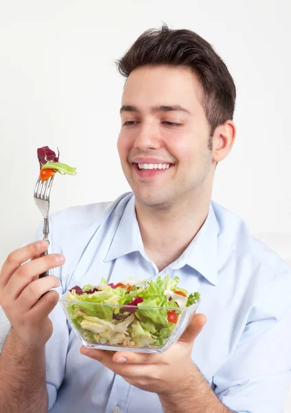 Riéndose chico hispano en un sofá ama ensalada verde — Foto de Stock