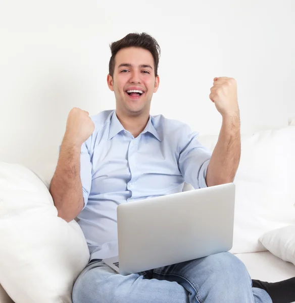 Succesvolle Spaanse man met laptop op een sofa — Stockfoto