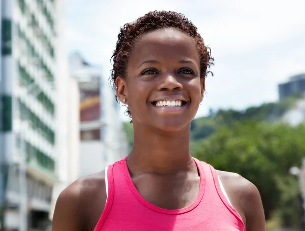 Chica afroamericana feliz en camisa rosa en la ciudad —  Fotos de Stock