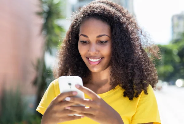 Schöne lateinische Frau mit lockigem Haar sendet Nachricht mit Telefon — Stockfoto