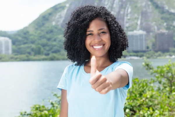 Mujer latina con pelo rizado negro al aire libre mostrando el pulgar hacia arriba —  Fotos de Stock