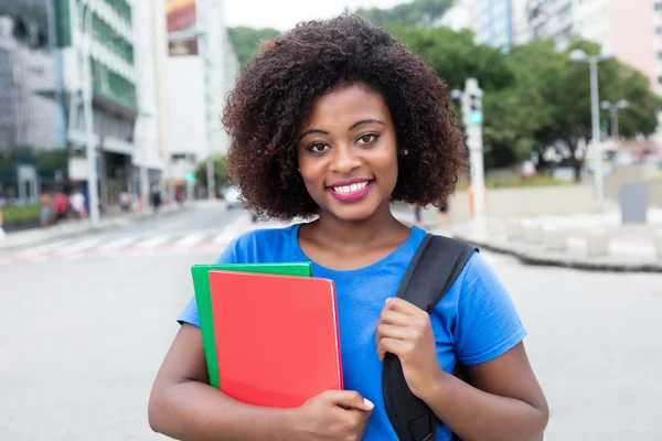 Śmiejąc się kobiet student z Afryki w niebieską koszulę w mieście — Zdjęcie stockowe