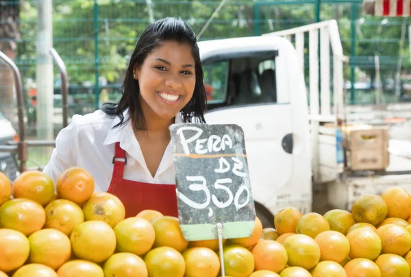 Felice commessa messicana con arance su un mercato contadino — Foto Stock