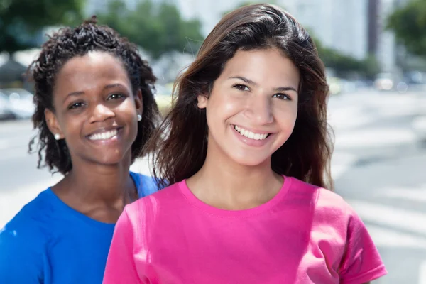 Lachen Kaukasische vrouw met Afrikaanse vriendin in de stad — Stockfoto