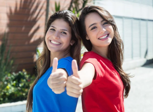 Две кавказские девушки показывают большой палец в городе — стоковое фото