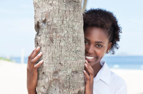 Mujer afroamericana feliz detrás de un árbol —  Fotos de Stock