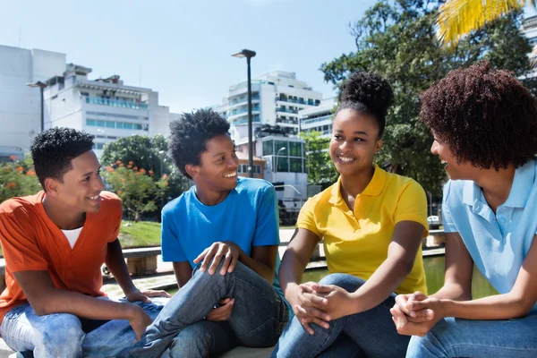 Grupo de cuatro adultos jóvenes latinoamericanos que hablan al aire libre — Foto de Stock