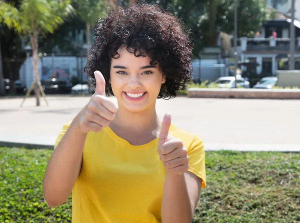 Caucásico chica con rizado negro pelo mostrando los pulgares —  Fotos de Stock