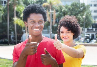 Afro-Amerikan erkek gösteren başparmak ile beyaz kız