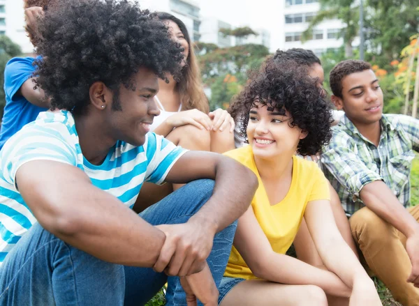 Afrikansk kille tala med Flickvän utomhus med multietnisk gr — Stockfoto