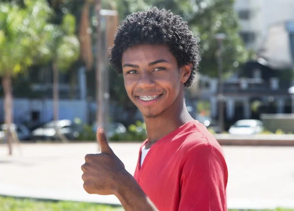 Latinoamericano ragazzo con dentatura bretelle mostrando pollice — Foto Stock