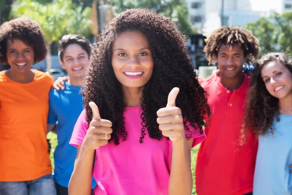 Latin woman with long curly hair showing thumbs up with friends — Stock Photo, Image