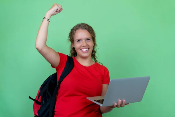 Happy german female student with computer cheering about graduation and good grades isolated on green background