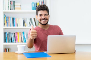 Sakallı yakışıklı Latin Amerikalı adam evdeki bilgisayardan internetten alıyor.