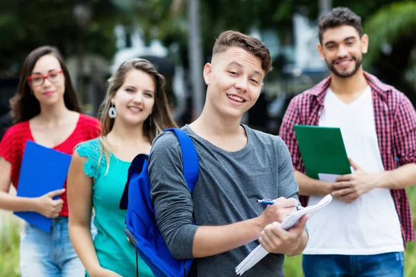 Smart german male student with group of other students outdoor in summer in city