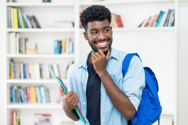 Üniversite kütüphanesinde sakallı yakışıklı Afro-Amerikan erkek öğrenci.