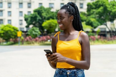 Güzel Afrikalı Amerikalı bir kız. Telefonu var. Yazın dışarıda mesaj yolluyor.