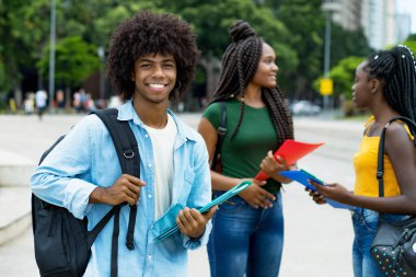 Yakışıklı afro-amerikan erkek öğrenci ve bir grup genç yetişkin yazın şehir dışında.