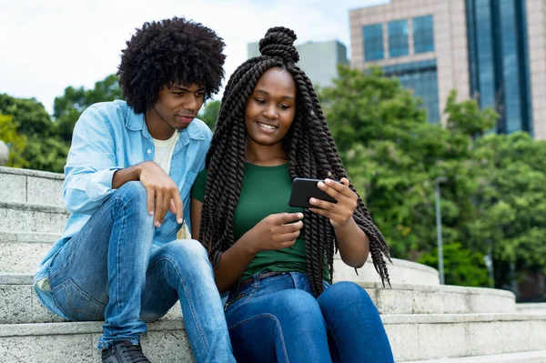 若いアフリカ系アメリカ人男性と女性のインフルエンサー夏に市内の携帯電話の屋外でメッセージを投稿 — ストック写真