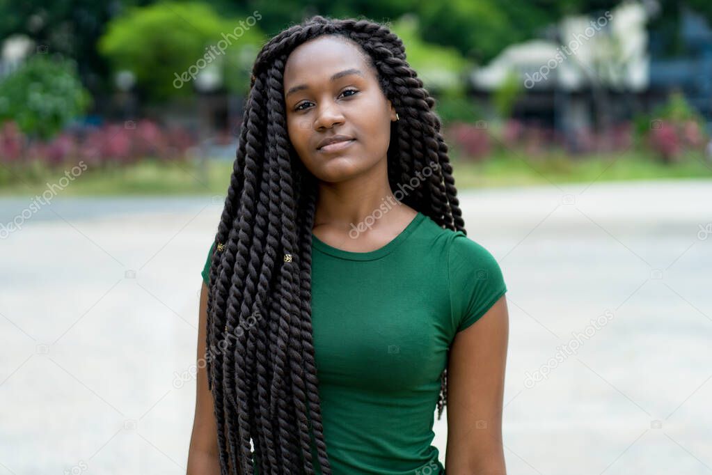 Beautiful young adult woman from Africa with amazing hairstyle outdoor in summer in city