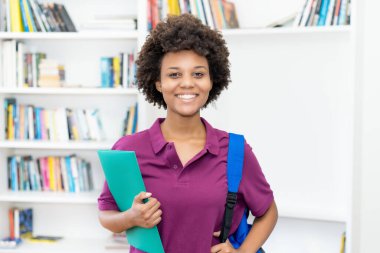 Üniversite sınıfında sırt çantası ve evrak işleriyle uğraşan Afro Amerikalı güzel bir bayan öğrenci.