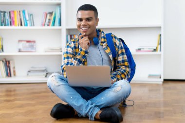 Evde bilgisayar başında diş teli programlama yazılımı olan İspanyol erkek öğrenci.