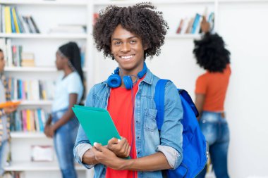 Üniversitenin kütüphanesindeki neşeli Afro-Amerikan erkek üniversite öğrencisi
