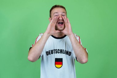 Yeşil arka planda futbol formasıyla Almanya 'dan futbol taraftarı diye bağırıyor.