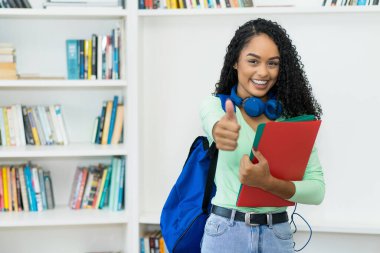 Brazilian female college student with braces showing thumb up at classroom