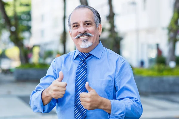 Laughing mexican senior businessman showing both thumbs up
