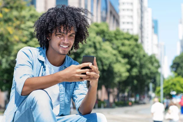 Nevető Latin Amerikai Fiatal Felnőtt Férfi Üzenetet Küld Mobiltelefonnal Kültéri — Stock Fotó