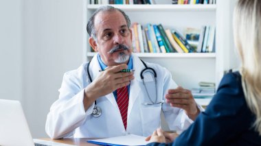 İspanyol erkek doktor klinikteki kadın hastaya hastalığı açıklıyor