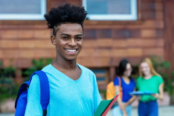 Şehirdeki bir grup uluslararası öğrenciyle yakışıklı Afro-Amerikan erkek öğrenci.