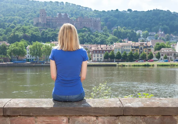 Wanita muda duduk di tepi sungai di Heidelberg — Stok Foto