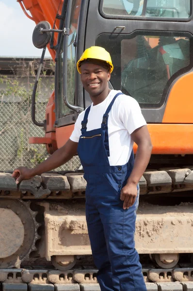 Muscular african american construction worker with excavator — Stock Photo, Image