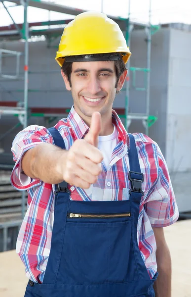 Hispanic construction worker at building site with showing thumb — Stock Photo, Image