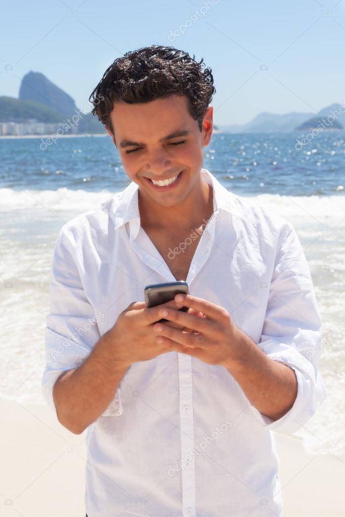 Attractive guy typing message at Copacabana beach