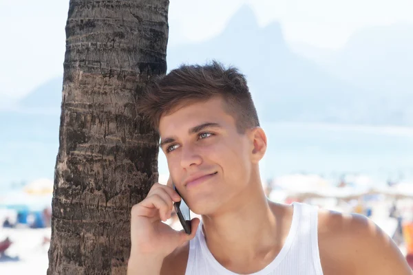 Sportig kille lyssnar på telefon på stranden Ipanema i Rio de Janeiro — Stockfoto