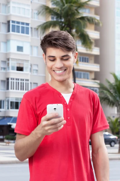 Hispanic guy in the city typing message at phone — Stock Photo, Image