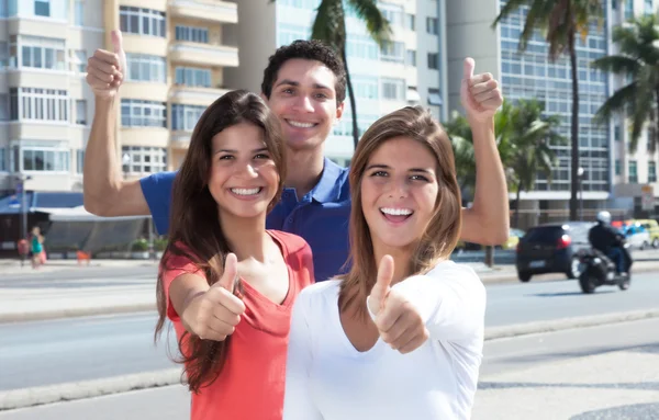 Três jovens na cidade mostrando o polegar para cima — Fotografia de Stock